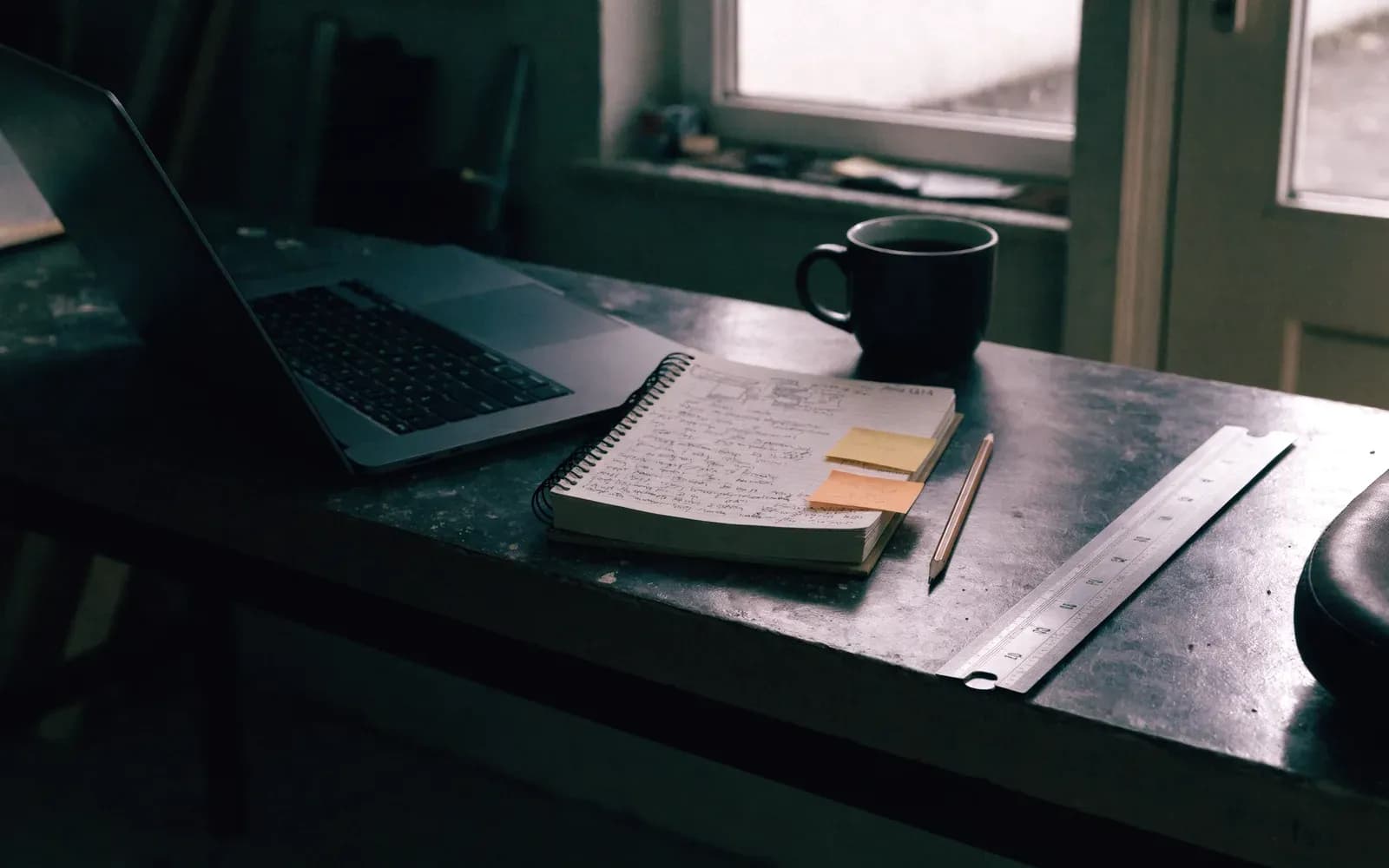 Werkbank met een laptop en een volgeschreven notitieblok